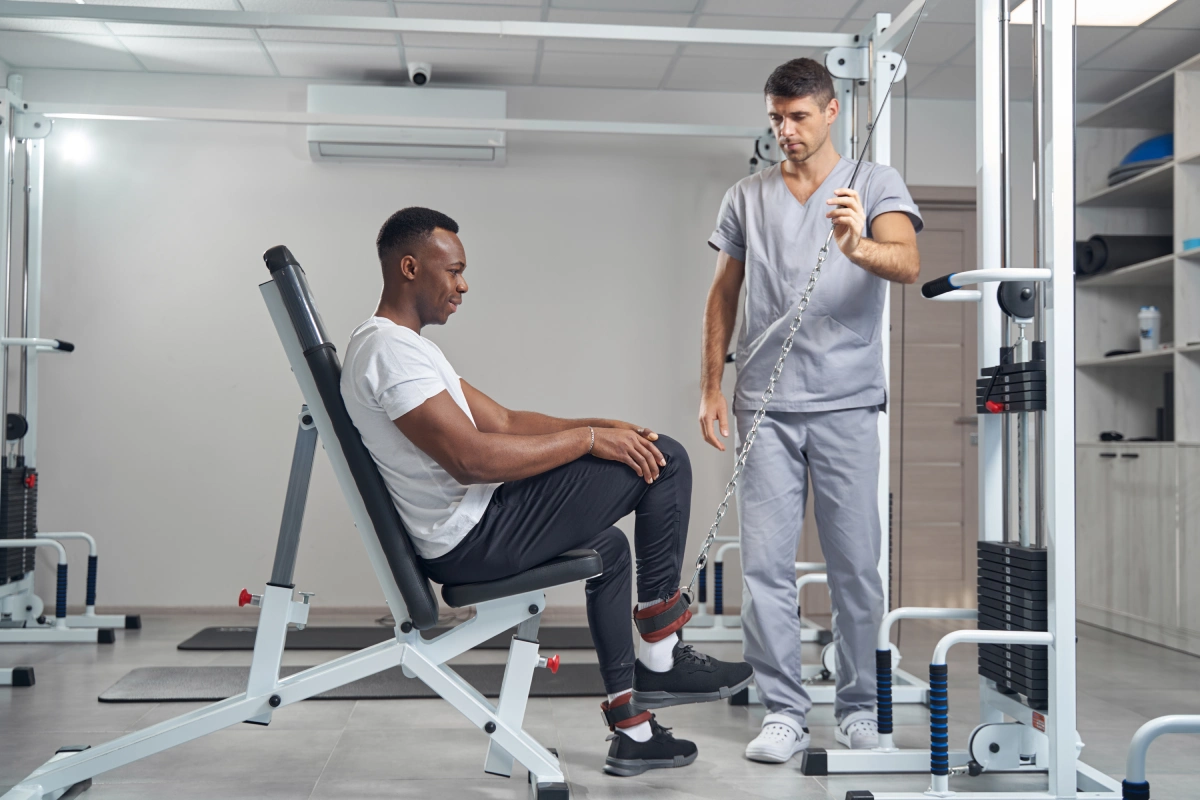 Physiotherapeut begleitet einen Patienten beim Gerätetraining